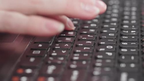 Female Hand Typing on Keyboard While Working at Computer Closeup