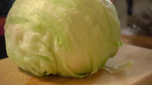 Slicing Fresh Iceberg Lettuce on Cutting Board