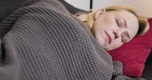 Woman Resting Comfortably on a Couch with Blanket