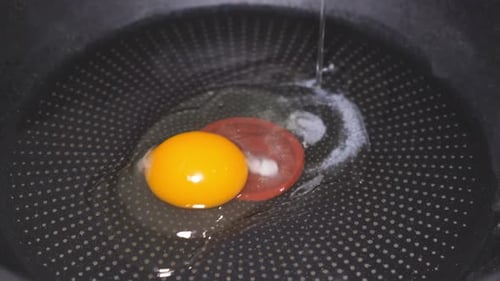 In Zeitlupe wird das Ei in eine Pfanne gebrochen und bei schwacher Hitze gebraten