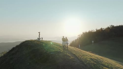 Fit couple walking and hiking to the top of the hill. Enjoying and exploring green countryside.