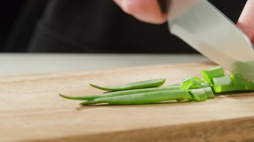 Chef Cutting Bunch of Green Onion Feathers By Knife on a Cutting Board on Professional Restaurant
