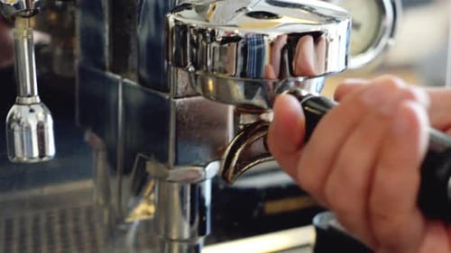 A barista tamping coffee grounds and inserting into the coffee machine | Gourmet Coffee House | Shot