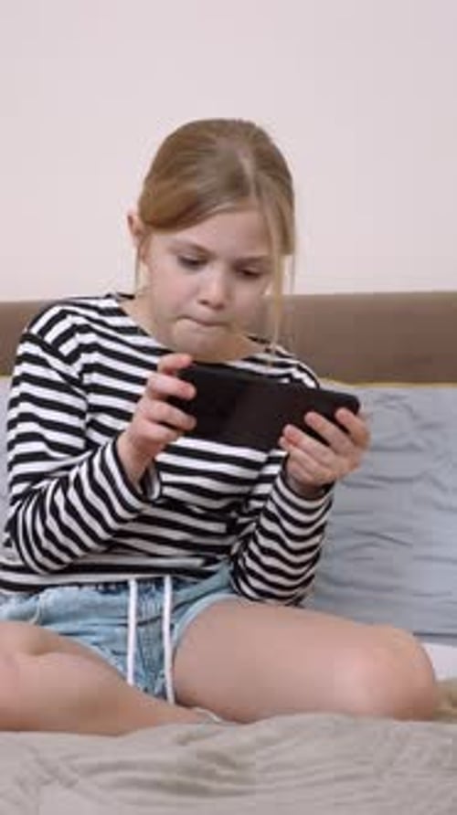 Girl Playing Game on Phone Indoors on Bed