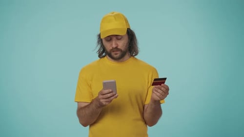 Man with Phone and Credit Card on Blue Backdrop