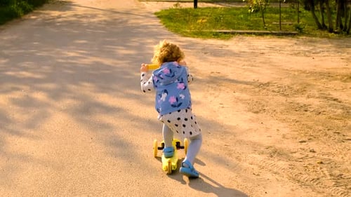 Young Child Scooting Through Park on Sunny Day