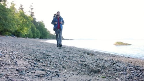 Mature man with backpack enjoys freedom and happiness on rugged ocean beach