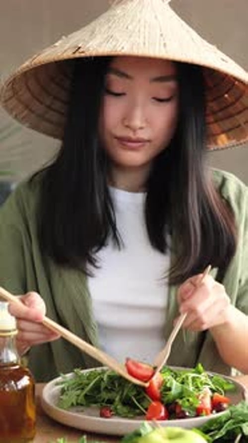 Woman with Asian Conical Hat Eats Salad Indoors