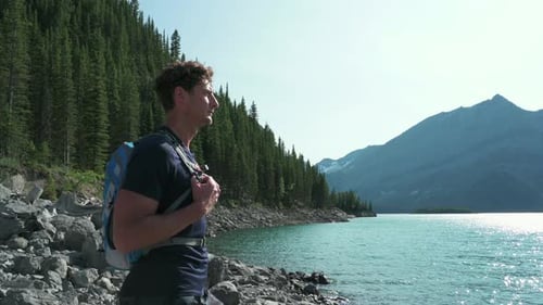 Mature man introspective gaze at sunny mountain lake serenity and adventure