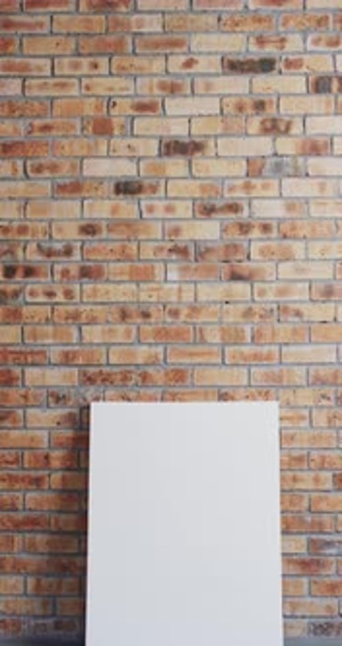 Vertical video of white canvas sign with copy space on floor against brick wall background