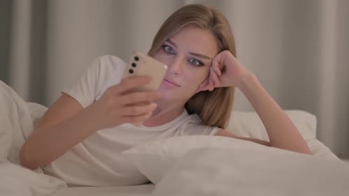 Woman Using Cellphone While Relaxing in Bed