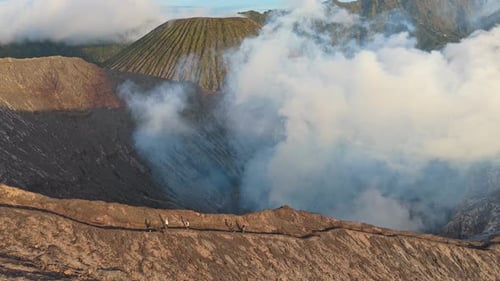 Tourists walking on mount bromo volcano crater rim in indonesia