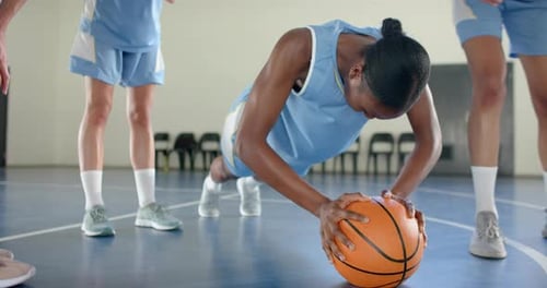 Exercising in gym, female basketball player doing push-ups using basketball