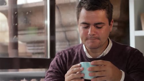 Thoughtful Man Enjoying a Warm Drink at the Cafe Window