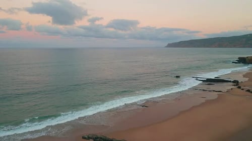 Calm Waves Crashing Shoreline Drone View Cloudy Sunset Illuminating Coastline