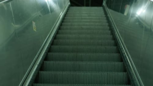 Empty escalator in a quiet, dimly lit metro station, conveying a sense of stillness and urban solitu