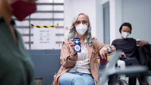 Woman displays digital covid pass on phone at airport