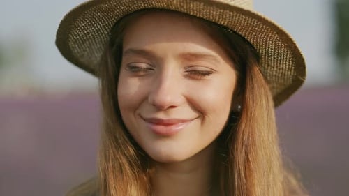 Portrait d'une belle jeune femme caucasienne joyeuse sur un champ de fleurs flou à l'extérieur, attrayante et heureuse