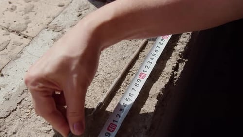 Measuring Construction Nail with Tape Measure on Site