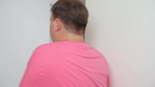Adult man hides behind wall in fear of imminent danger
