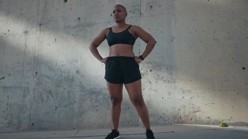 Confident Woman in Sports Bra Posing Against Concrete