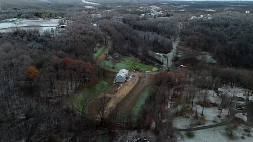 Aerial Orbit Over Muddy Farm in Snowy Morgantown with Winding Road in Forest