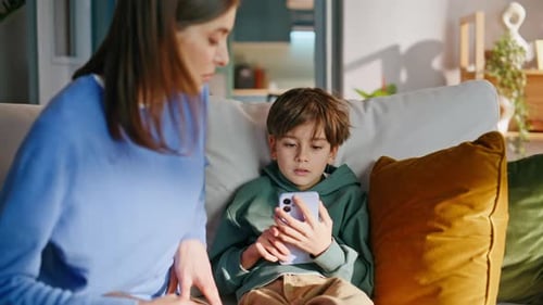 Caring Woman Comforts Boy with Phone on Sofa