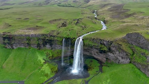 Majestic Waterfall Cascading Into Lush Green Valley in Icelands Breathtaking Landscape