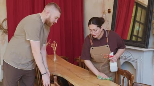 Waitress Cleaning Tables and Talking to Male Manager Helping in Cafe
