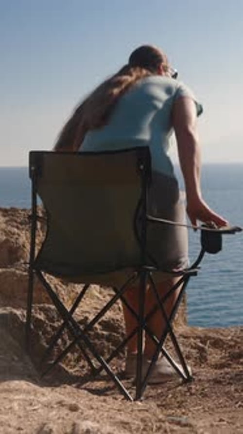 A man in a mask with a tattoo jumps into the sea from a cliff. Slow motion Vertical, Social Media.