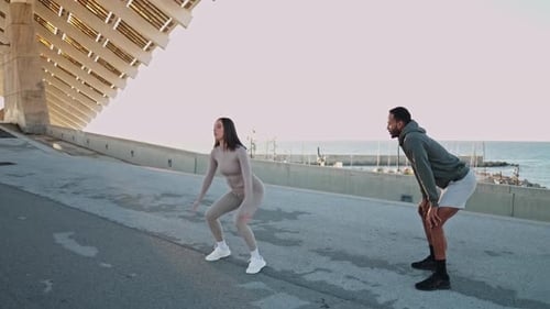 Woman Does Squat Jumps as Man Encourages