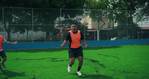 Latin and White teammates kick ball and score goal in urban soccer match, celebrating with cheers