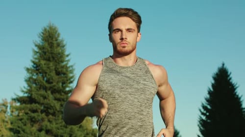 Athletic man running in sunny city park on a bright blue sky morning