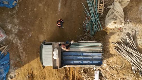 Construction Worker Dropping Metal Beams From the Car on the Ground Aerial View