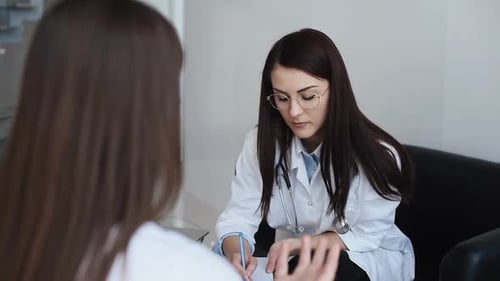 Looking at x-ray. Woman have a consultation in clinic with female doctor in white coat
