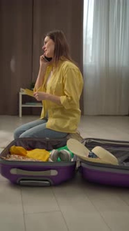 Smiling Woman Packing Suitcase while Talking on Phone