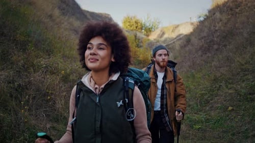 Couple Hiking with Backpacks on a Grassy Trail