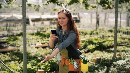 Woman records a video about plants in greenhouse