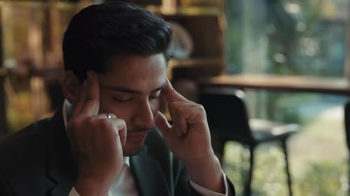 Portrait of Exhausted Indian Man with Closed Eyes Massages Temples in Office