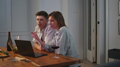 Couple Using Laptop Computer at Table With Wine