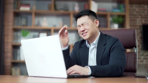 Stressed Businessman Using Laptop in Office