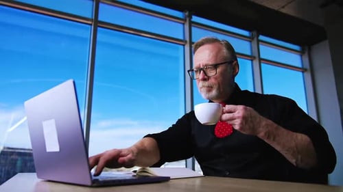 Adult Typing at Laptop with Coffee by Window