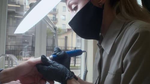 Manicurist Filing Person's Nails with Electric File Close Up