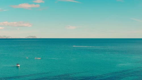 Small boats and yachts anchored and Stand up Paddles SUP floating through the turquoise waters of