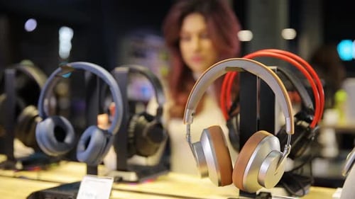 Cheerful Young Woman Buying New Headphones in Tech Store Department