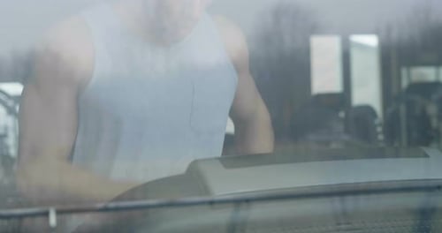 A guy in the gym to stay fit and have defined muscles or lose weight runs on the treadmill with a