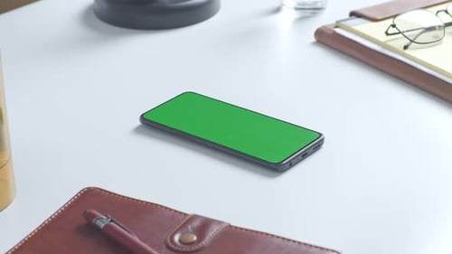 Close up of a mock up green screen chromakey smartphone on a desk at the office