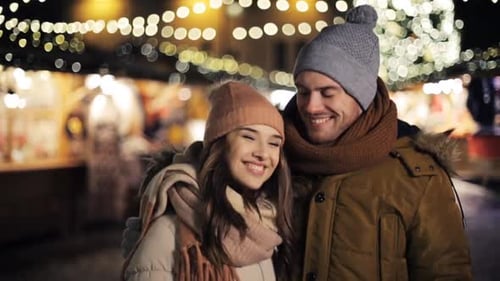 Love, Winter Holidays And People Concept - Happy Couple Hugging At Christmas Market In Evening