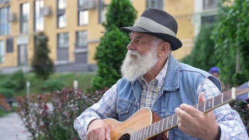 Senior Man Plays Guitar Outdoors in Urban Setting