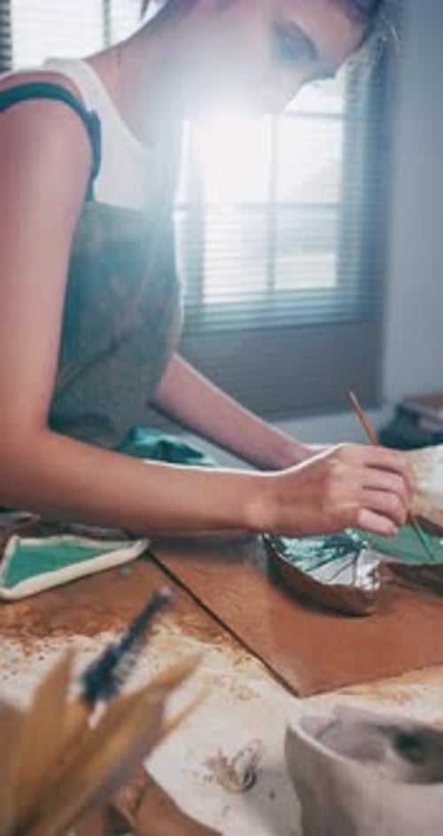A female ceramicist is creating a new pottery in the workshop.